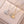 Two pearl pendants on gold and silver chains on a beige surface