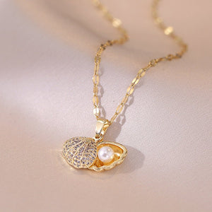Two necklaces, one with a silver shell-shaped pendant and the other with a gold shell-shaped pendant, both with pearl details, displayed on a beige background.