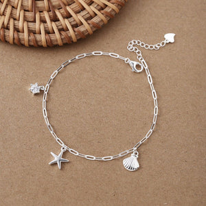 Silver anklet with starfish and shell charms on a brown background