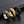 Three spinner rings, one gold, one silver, and one black with starfish and shell designs on a dark textured surface.