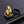 Three spinner rings, one gold, one silver, and one black with starfish and shell designs on a dark textured surface.