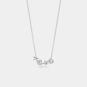 Silver necklace with starfish pendant on a light gray background