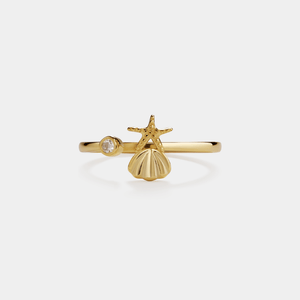 Gold ring with starfish and shell design on a white background