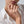 Close-up of a hand wearing a gold ring with starfish and shell design on a white background