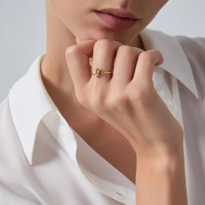Close-up of a hand wearing a gold ring with starfish and shell design on a white background