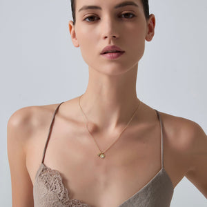 Woman wearing a delicate necklace against a plain background