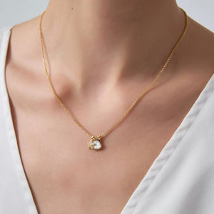 Gold necklace with a heart-shaped pendant on a neutral background
