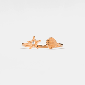 Rose gold ring with starfish and shell design on a light gray background