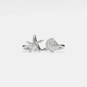 A silver-colored ring featuring a starfish and a seashell design, crafted from solid 925 sterling silver with a hypoallergenic finish.