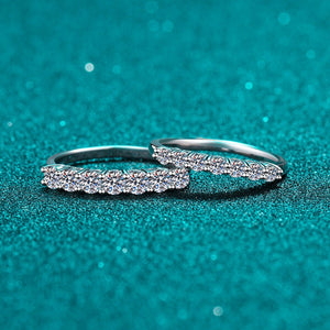 Two silver rings with diamond accents on a teal background