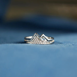 Silver mountain-shaped ring on a blue fabric background
