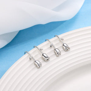 Silver floral earrings on a white plate with a blue background