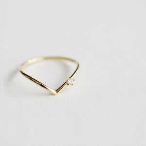 Gold ring with a small diamond on a light gray background