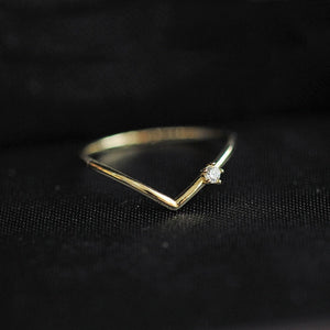 Gold triangle-shaped ring with a diamond on a black background