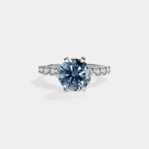 Diamond ring with a blue gemstone on a light gray background