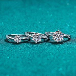 Three silver rings with diamond-like stones on a teal background