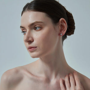 Woman with a bun hairstyle and earring on a plain background