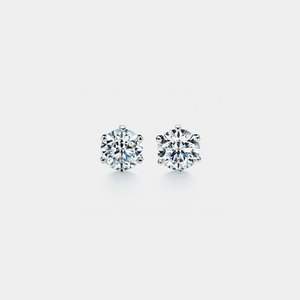 A pair of round moissanite stones set in silver stud earrings against a white background.