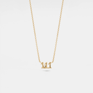 Gold necklace with a small pendant on a light gray background