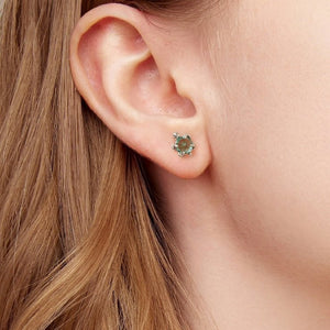 Close-up of an ear wearing a blue gemstone sea turtle stud earring with blonde hair.