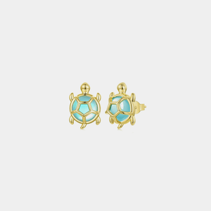 Gold sea turtle-shaped earrings with blue cubic zirconia centers on a light gray background