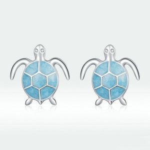 Sea turtle-shaped earrings with blue enamel design on a light gray background