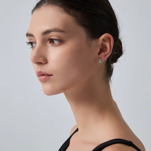 Close-up of a woman wearing sea turtle earrings on a plain background