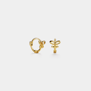 Two gold bow-shaped earrings on a light gray background
