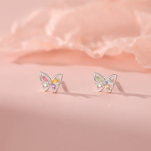 Butterfly-shaped earrings with colorful stones on a pink satin background