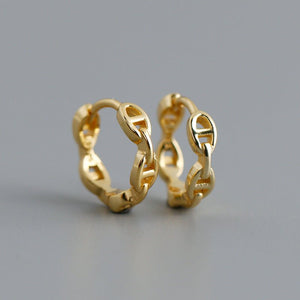 A set of small chain link huggie hoop earrings in silver and gold colors, displayed against a grey background.