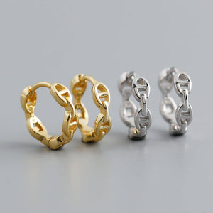 Pair of gold hoop earrings and a pair of silver hoop earrings on a light gray background