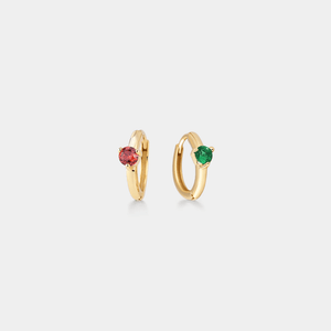 Gold hoop earrings with red and green gemstones on a light gray background