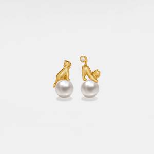 Gold monkey earrings with pearl balls on a light gray background