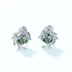 Silver earrings with green gemstones on a white background