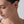 Close-up of a woman wearing a silver earring on a plain background