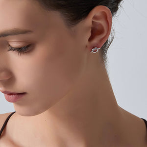 Close-up of a woman wearing a silver earring on a plain background