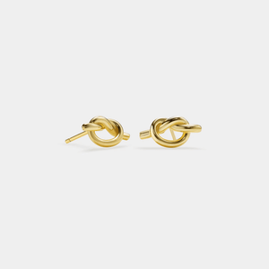 Pair of gold knot-shaped earrings on a light gray background
