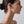 Close-up of a woman's profile wearing a silver earring on a plain background