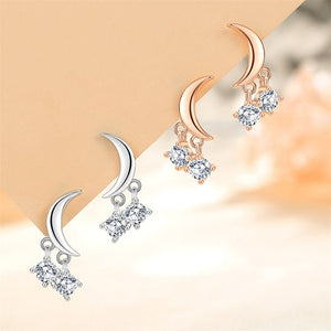 Pair of moon-shaped earrings with diamond-like stones on a gradient background