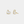 Heart-shaped earrings with gold frame and white center on a light gray background