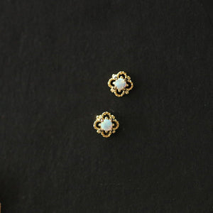Pair of gold earrings with opal stones on a black background
