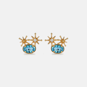 Gold earrings with blue gemstones on a light gray background