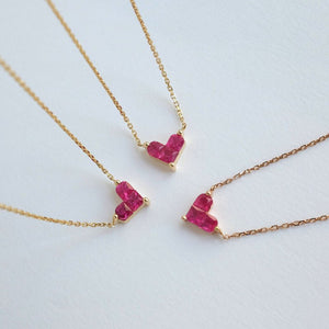 Three gold necklaces with pink gemstone pendants on a white background