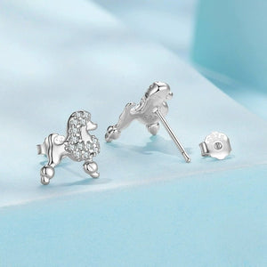 Silver poodle-shaped earrings on a light blue background