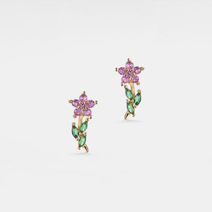 Pair of floral earrings with pink and green gemstones on a light gray background