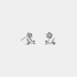 A pair of gold-colored rose flower stud earrings with cubic zirconia accents on a white background.
