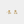 Gold earrings with diamond accents on a light gray background