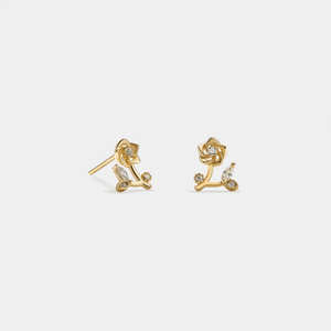 Gold earrings with diamond accents on a light gray background