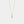 Gold necklace with a small green gemstone pendant on a light gray background