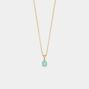 Gold necklace with a small green gemstone pendant on a light gray background
